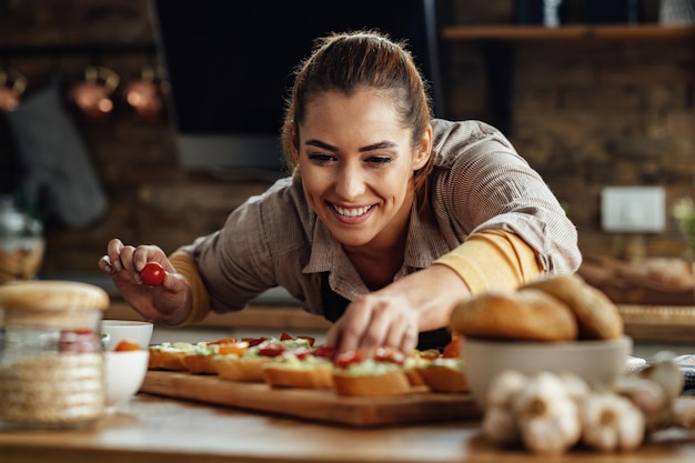 Junge glückliche Frau bereitet gesundes Essen zu, während sie Bruschetta in der Küche macht