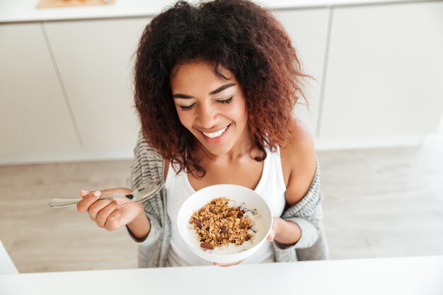 Junge glückliche Frau, die Frühstück in der Küche isst