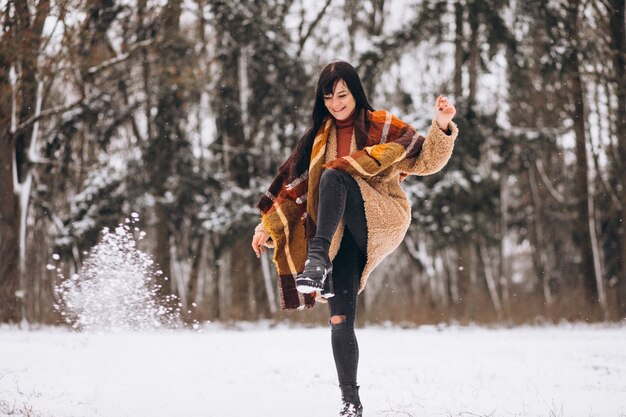 Junge glückliche Frau in den warmen Stoffen in einem Winterpark