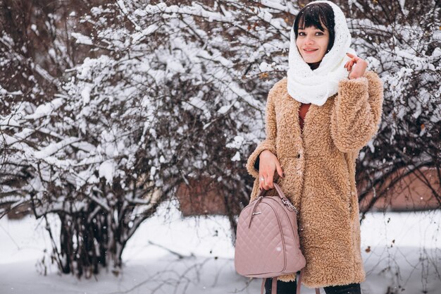 Junge glückliche Frau in den warmen Stoffen in einem Winterpark