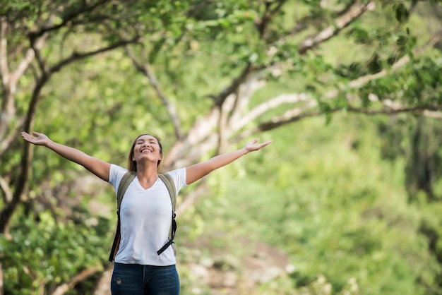 Junge glückliche Frau mit dem Rucksack, der Hand anhebt, genießen mit Natur.