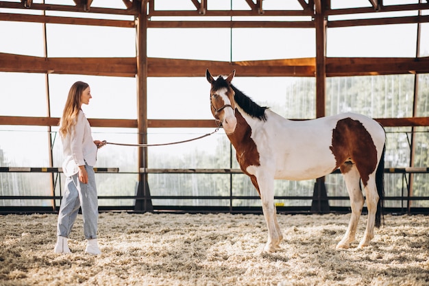 Junge glückliche Frau mit Pferd an der Ranch