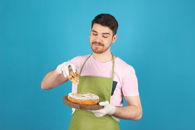 Junge glückliche Mann Takin Kuchenscheibe auf einem Blau.