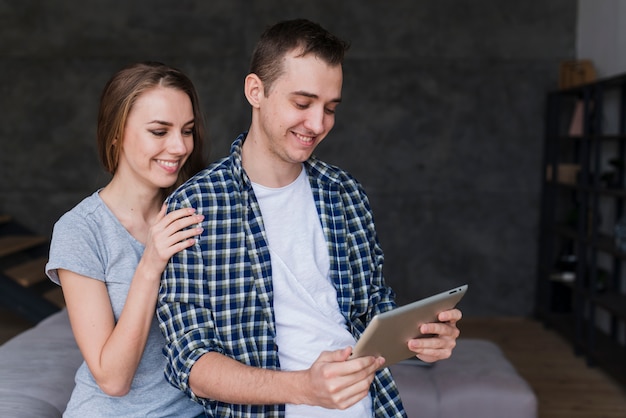 Kostenloses Foto junge glückliche paargrasertablette auf sofa