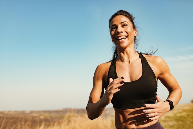 Junge glückliche sportliche Frau, die Spaß beim Joggen in der Natur hat Kopieren Sie Platz