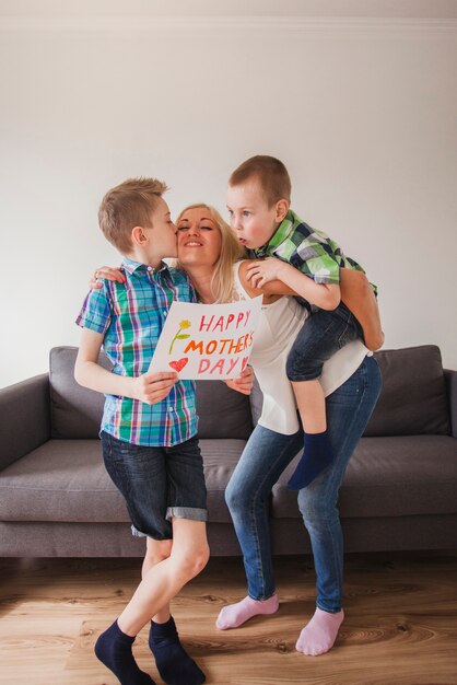 Junge hält ein Plakat und küsst seine Mutter