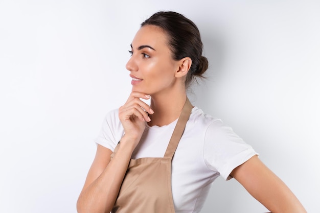 Junge Hausfrau in einer Schürze auf weißem Hintergrund mit einem glücklichen Lächeln auf ihrem Gesicht süß positiv