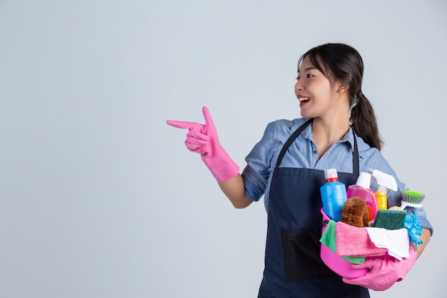 Junge Hausfrau trägt gelbe Handschuhe beim Putzen mit dem Produkt von sauber auf weißer Wand.