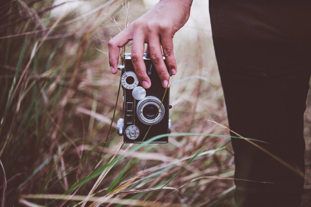 Junge Hippie-Frau Fotos mit Vintage Filmkamera im Sommer Feld zu machen. Frauen-Lifestyle-Konzept.