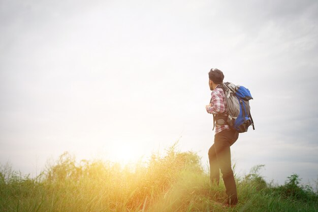 Junge Hippie-Mann im Freien mit Rucksack auf der Schulter, Zeit zu