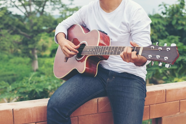 Junge Hippie-Mann spielt Gitarre auf seinem Urlaub, enj zu entspannen