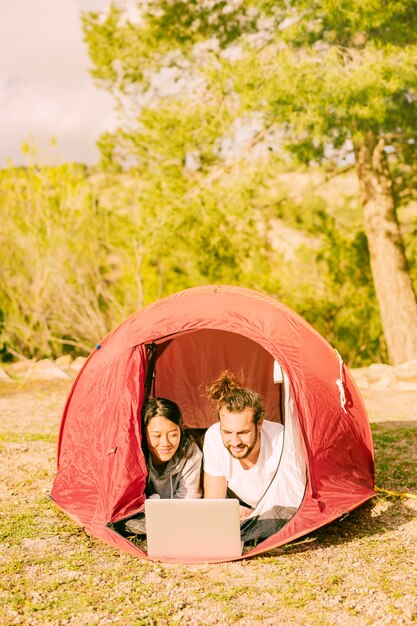 Junge Hippies, die im Zelt mit Laptop sich entspannen