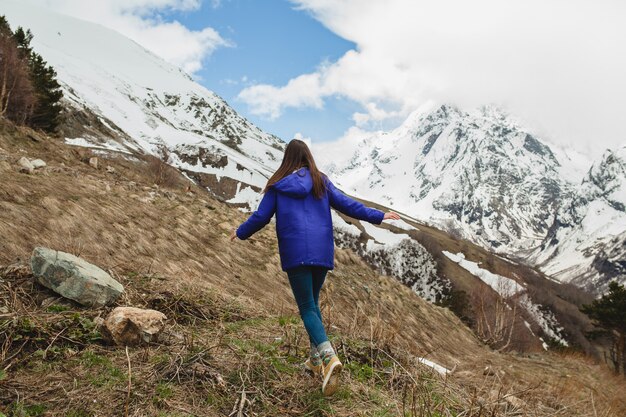 Junge Hipsterfrau, die in den Bergen geht