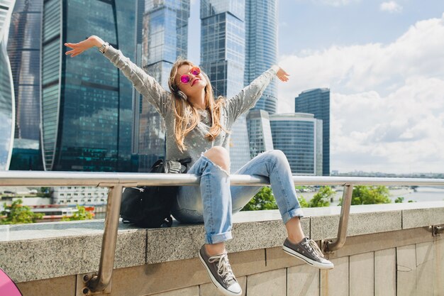 Junge Hipsterfrau, die Spaß in der Straße hat, die Musik auf Kopfhörern hört