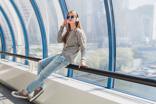 Junge Hipsterfrau im lässigen Outfit, das Spaß hat, Musik in den Kopfhörern zu hören