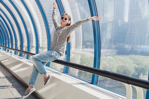 Junge Hipsterfrau im lässigen Outfit, das Spaß hat, Musik in den Kopfhörern zu hören