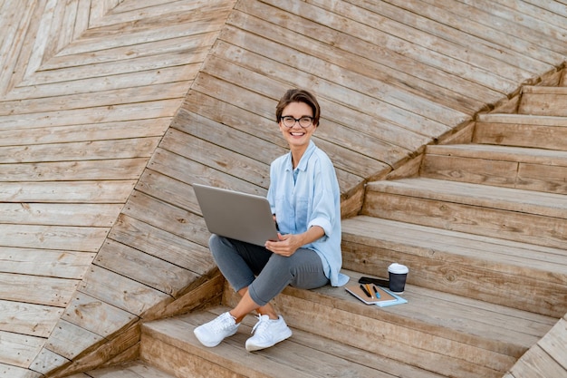 Junge hübsche Frau, die am Laptop in der modernen Parkstraße arbeitet