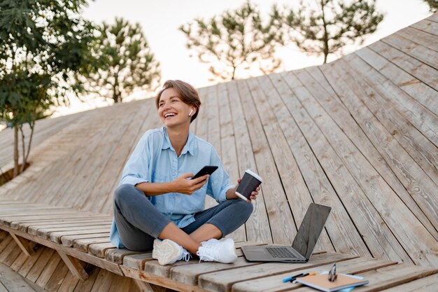 Junge hübsche Frau, die am Laptop in der modernen Parkstraße arbeitet