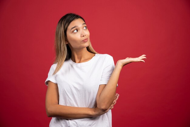 Junge hübsche Frau, die auf roter Wand aufwirft.