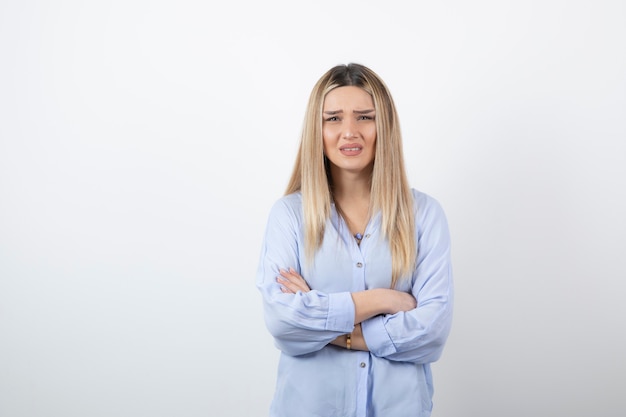 junge hübsche frau, die auf weißer wand steht.