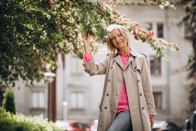 Kostenloses Foto junge hübsche frau, die durch die blumen im park steht