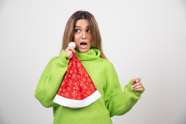 Junge hübsche Frau, die im roten Hut des Weihnachtsmanns aufwirft