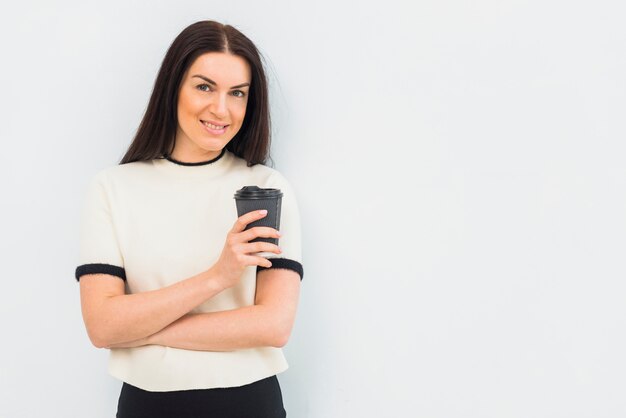 Junge hübsche Frau, die mit Kaffeetasse steht