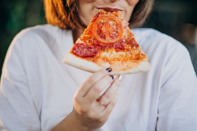 Junge hübsche Frau, die Pizza an einer Bar isst