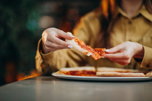 Junge hübsche Frau, die Pizza an einer Bar isst