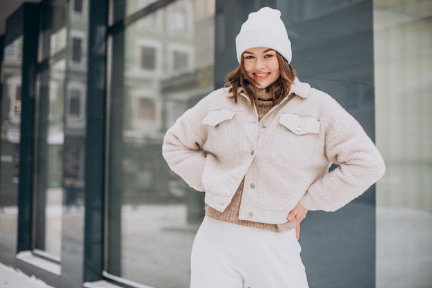 Junge hübsche Frau im beige Outfit, das zur Winterzeit auf der Straße geht