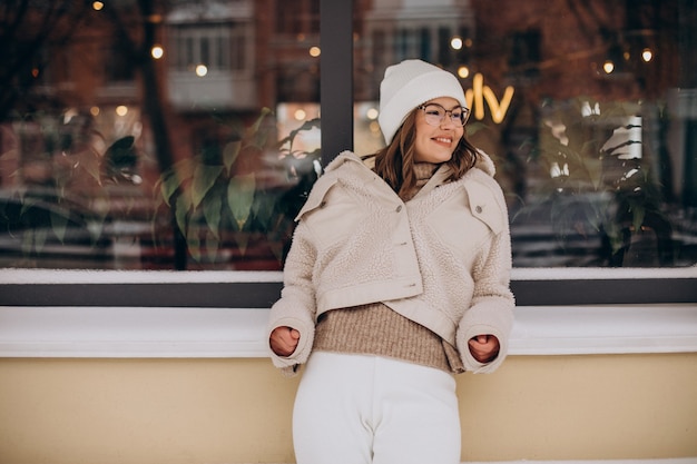 Kostenloses Foto junge hübsche frau im beige outfit, das zur winterzeit auf der straße geht