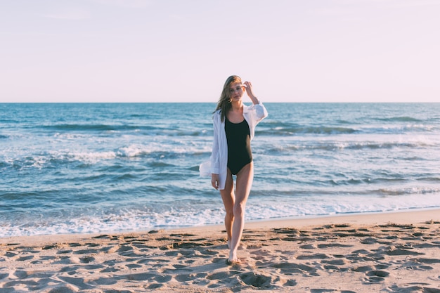 Junge hübsche frau im bikini am strand am sonnenuntergang