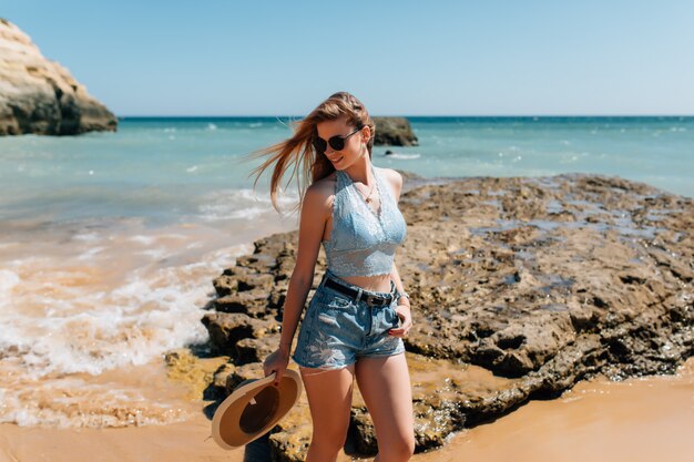 Junge hübsche Frau im Hut am Strand