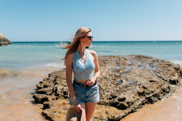 Junge hübsche Frau im Hut am Strand