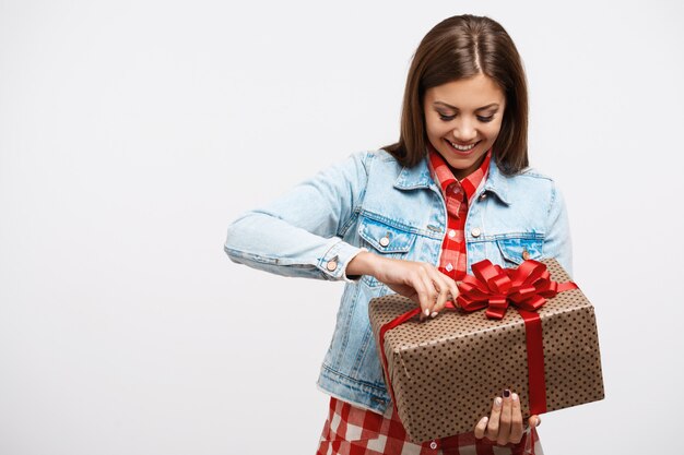 Junge hübsche Frau im Modefrühlingsoutfit, das Geburtstagsgeschenk öffnet