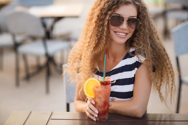 Junge hübsche Frau mit Cocktail auf der Caféterrasse