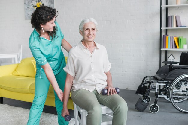 Junge hübsche Krankenschwester, die alte Frau in seiner Therapie unterstützt