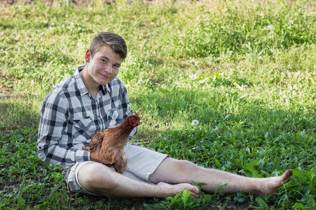 Junge im Gras, das mit Huhn spielt