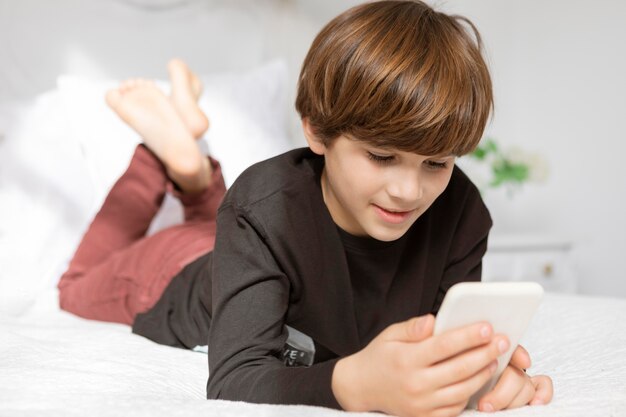 Junge im Schlafzimmer mit Telefon