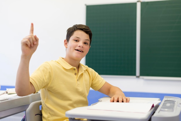 Kostenloses Foto junge in der klasse mit erhobenem finger