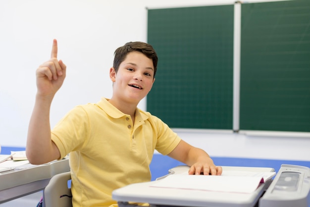 Junge in der Klasse mit erhobenem Finger