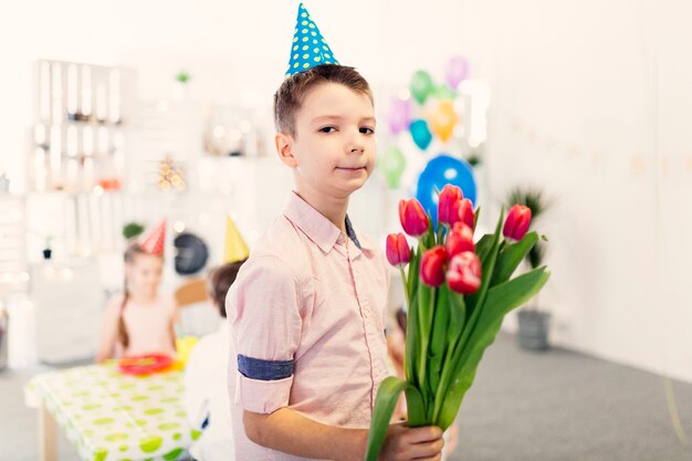 Junge in farbiger Kappe mit Blumen