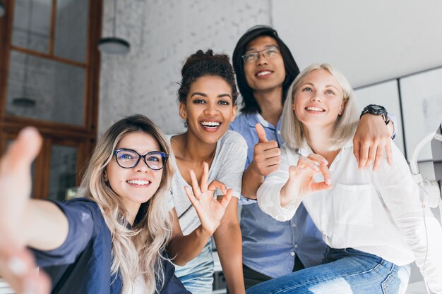 Junge internationale Büroangestellte posieren zusammen und lachen in der Pause