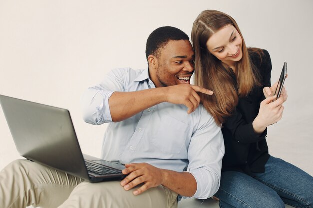 Junge internationale Paare, die zusammenarbeiten und den Laptop benutzen