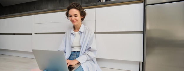 Junge IT-Mädchen Frau arbeitet freiberuflich von zu Hause sitzt auf dem Boden mit Laptop Mädchen Student macht Hausaufgaben