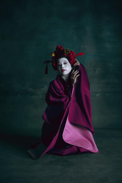 Junge japanische Frau als Geisha auf dunkelgrünem. Retro-Stil, Vergleich des Epochenkonzepts