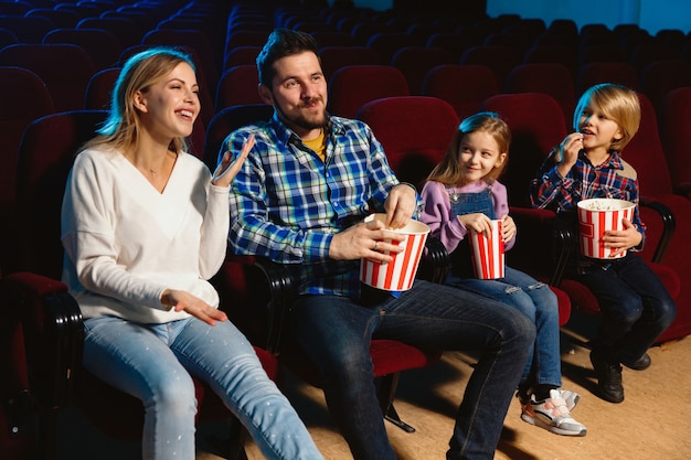 Junge kaukasische Familie, die einen Film in einem Kino, Haus oder Kino sieht. Sieh ausdrucksstark, erstaunt und emotional aus. Allein sitzen und Spaß haben. Beziehung, Liebe, Familie, Kindheit, Wochenendzeit.