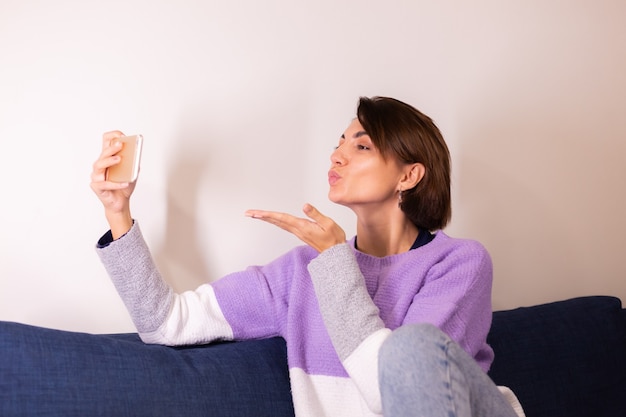 Junge kaukasische Mädchenfrau im Schlafzimmer auf Sofa Blick auf Handy-Kamera