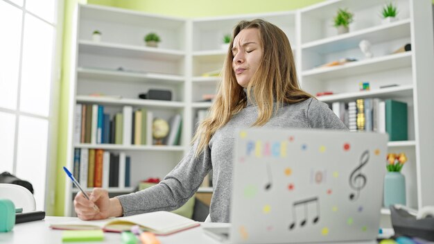 Junge kaukasische Studentin benutzt Laptop und schreibt auf Notebook an der Universitätsbibliothek