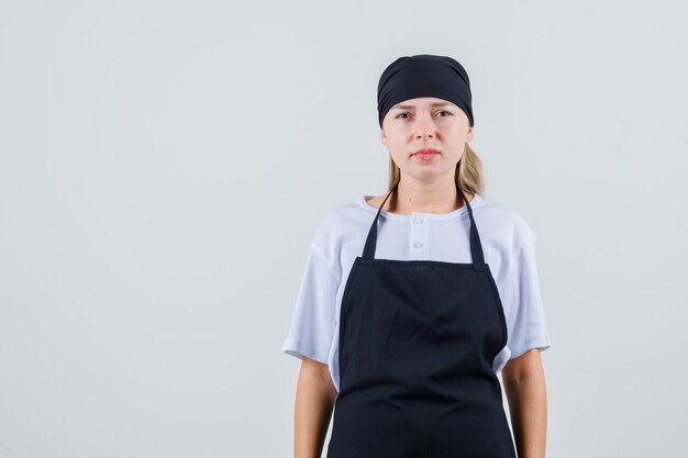 Kostenloses Foto junge kellnerin in uniform und schürze, die enttäuscht aussieht und aussieht